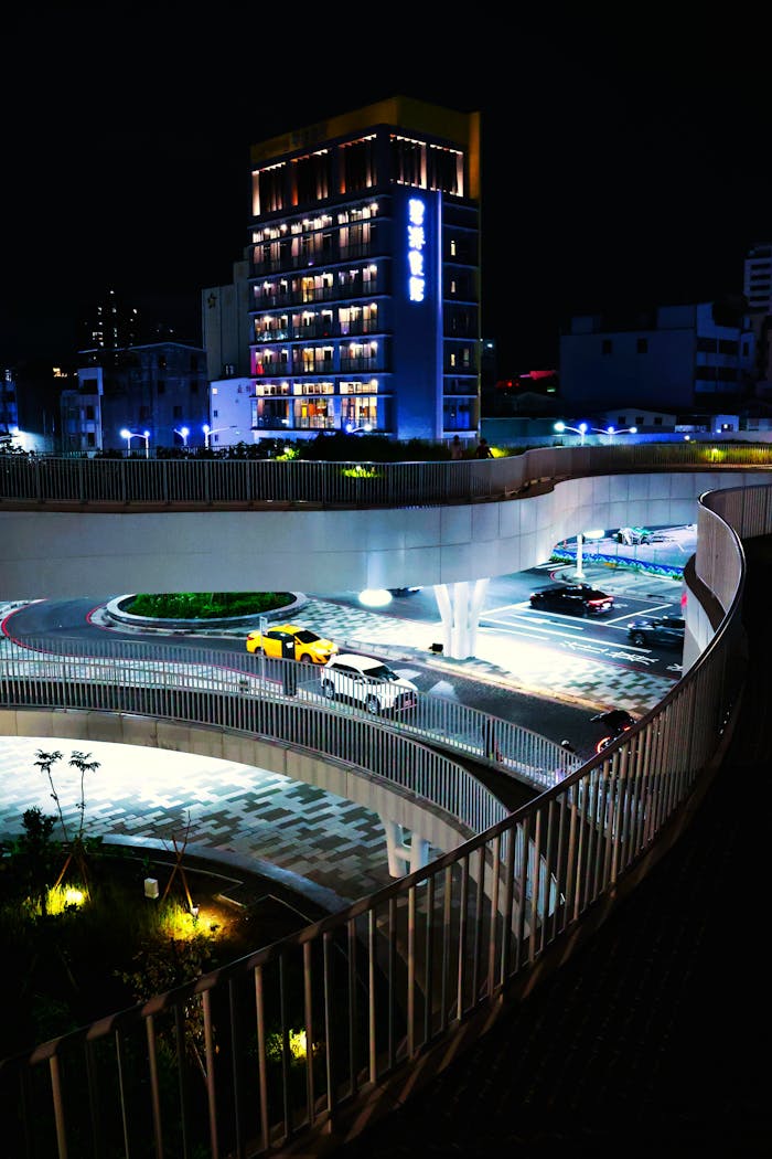 Brightly lit urban street with modern architecture and traffic in Taiwan at night, showcasing vibrant city life.