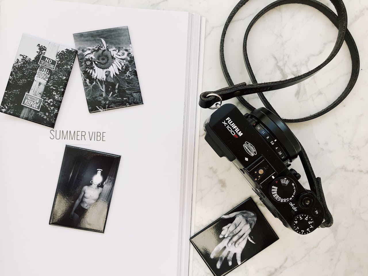 Creative flat lay with a vintage camera and artistic black-and-white photo prints on marble.